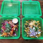 two reusable green boxes with nachos and salads